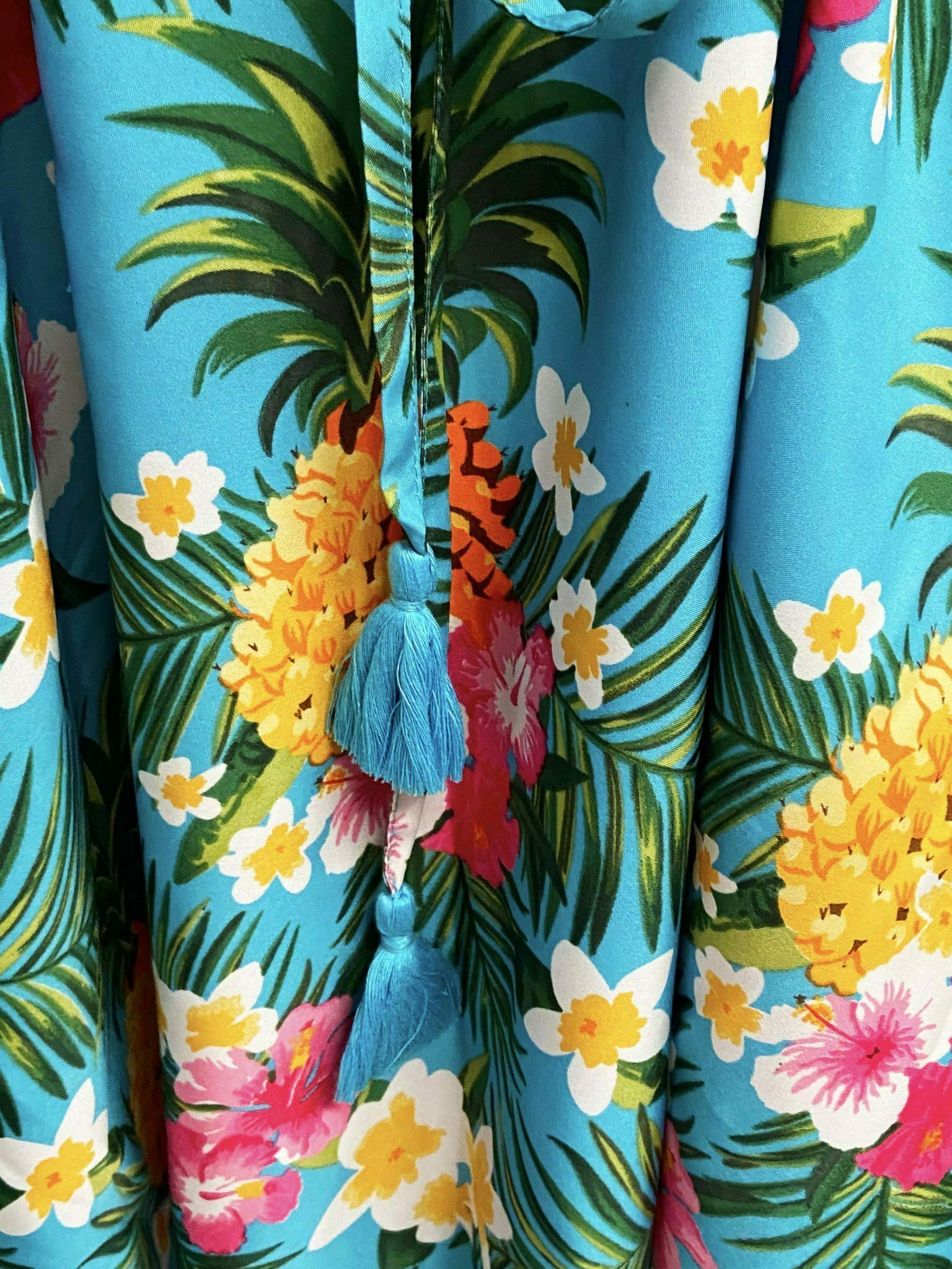 Repeating pattern tropical print with pineapples, frangipannis and palm fronds