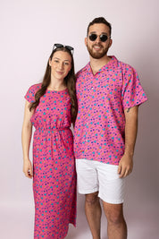Two people wearing matching pink outfits with a pattern on a plain background