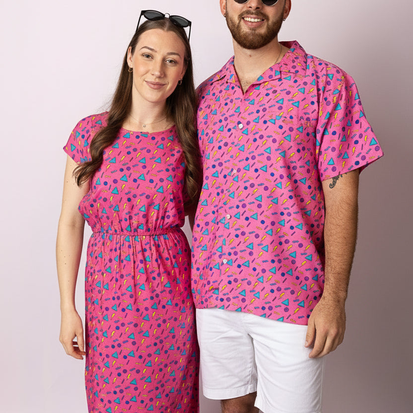 Two people wearing matching pink outfits with a pattern on a plain background