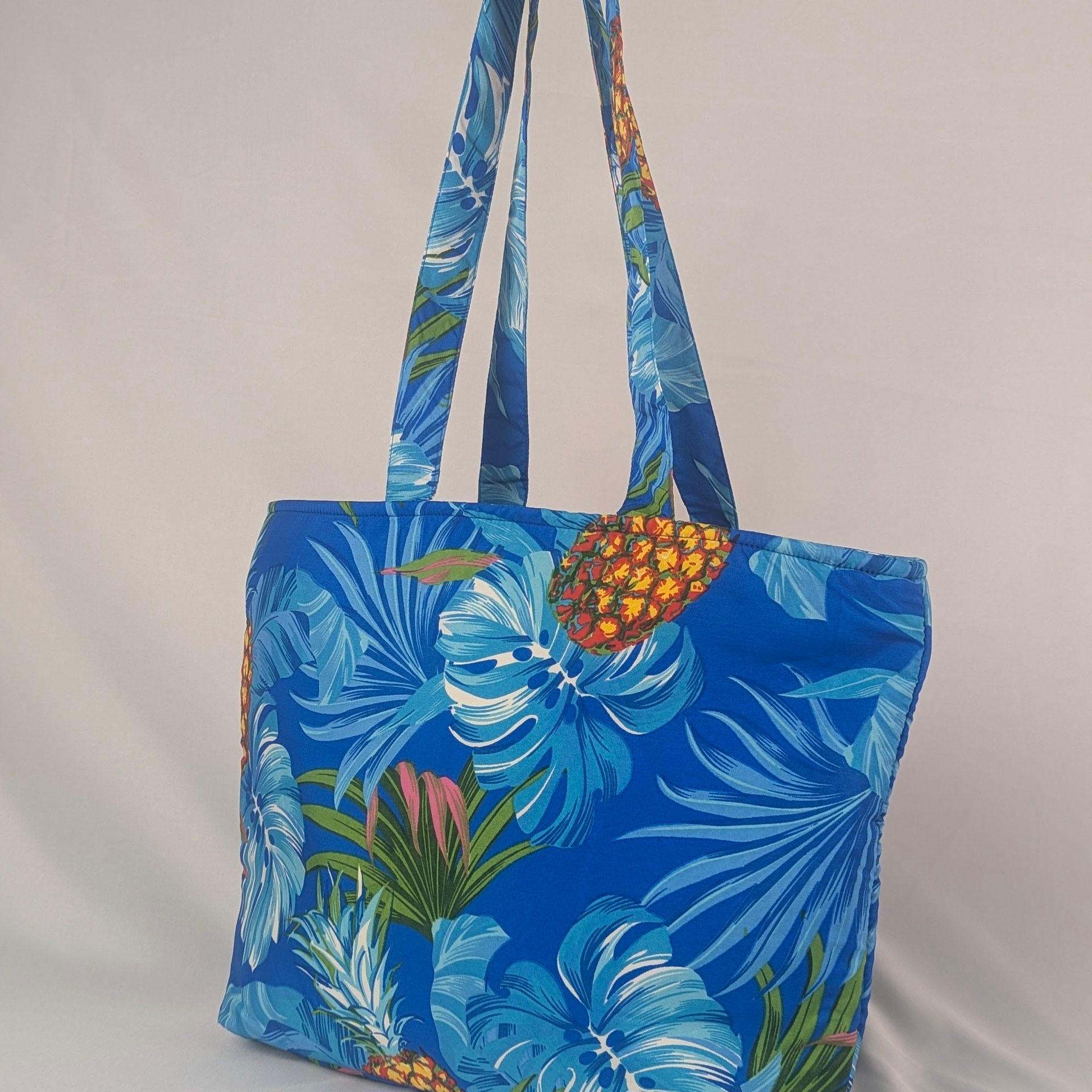 Tropicool Tote Bag with blue tropical leaves and pineapple print on a light background. Festive tote style. | Tropicool Clothing