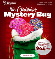 Promotional graphic for a Tropical Cool 'The Christmas Mystery Bag' featuring a green Santa sack with white faux fur trim, partially filled with colorful patterned shirts. The background is dark red with festive text, and a white ornament badge highlights the customizable size and print option.