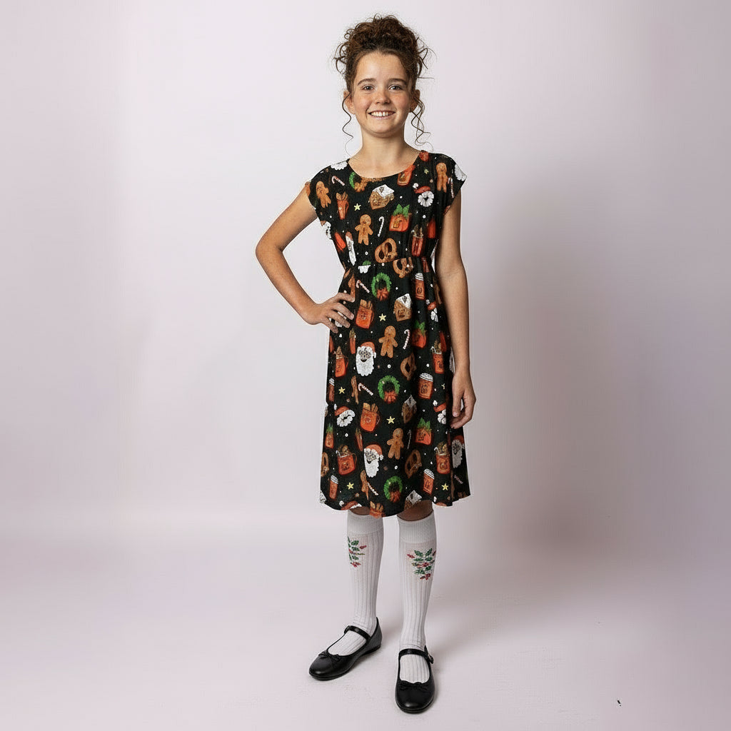 Girl wearing the Tropicool Holly Jingleverse Christmas Kids Dress in black with Rick and morty festive prints, standing with hands on hips