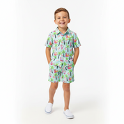 Kid wearing blue Christmas shorts featuring Santa on flamingo floats with palm trees and tropical festive patterns.