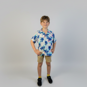 Child wearing a floral shirt and shorts on a plain background