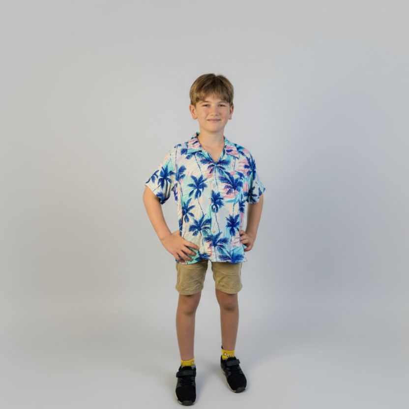 Child wearing a floral shirt and shorts on a plain background