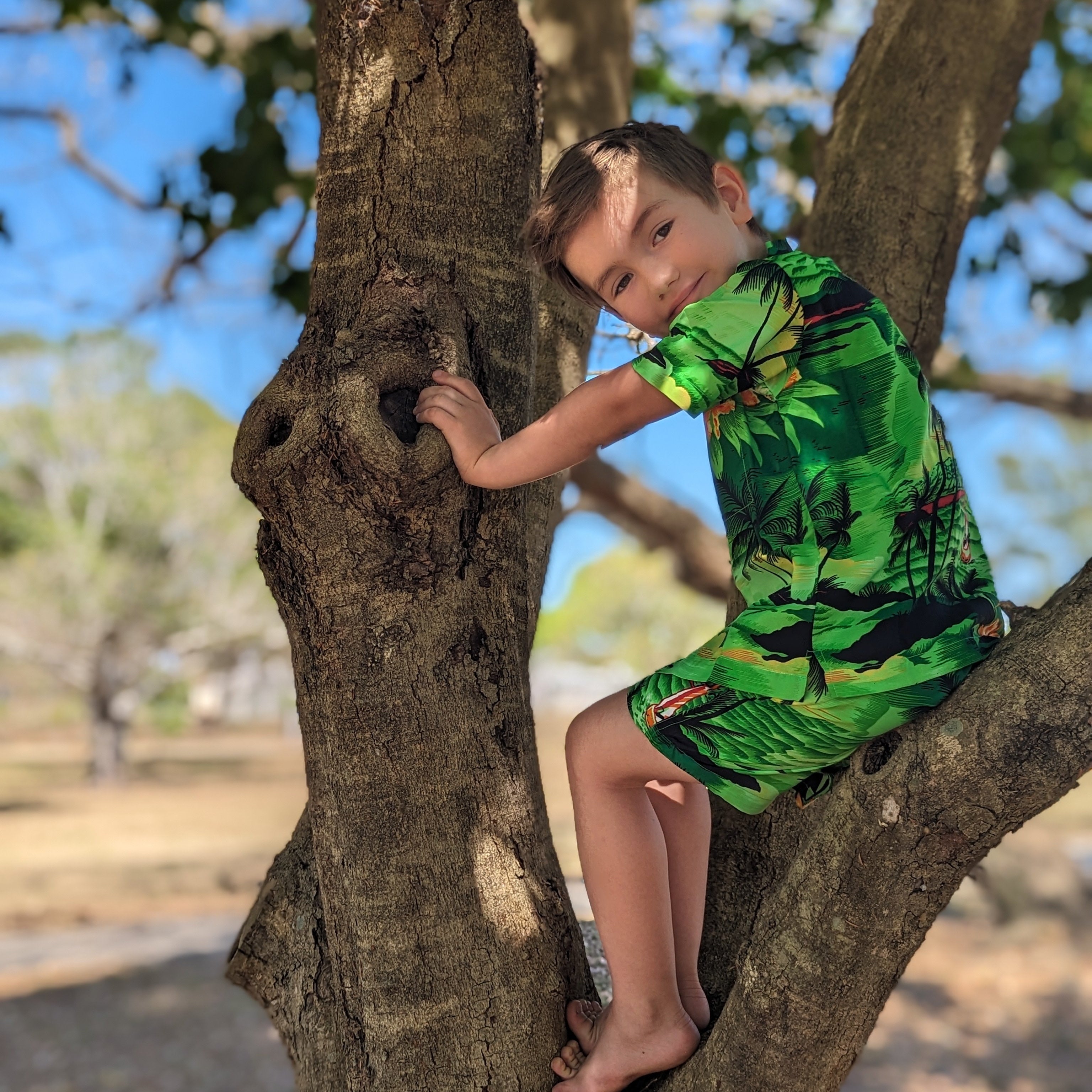 Sunset Green Kids Shirt features a vibrant tropical pattern, short sleeves, and festive summer colors. | Tropicool Clothing
