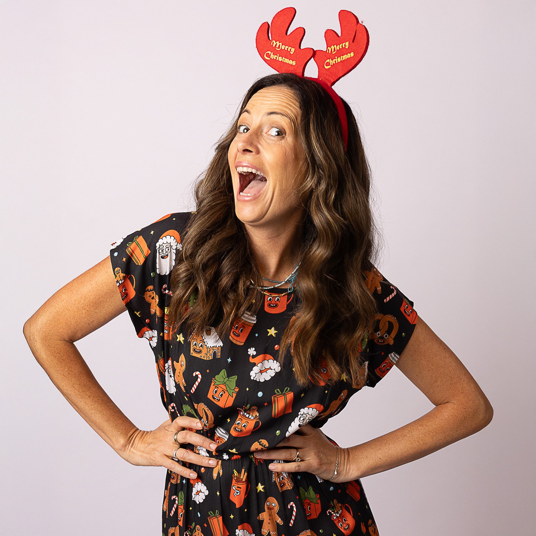 Woman wearing the Tropicool Alice JingleVerse Christmas adult dress in black rick & morty theme, smiling with festive antlers.