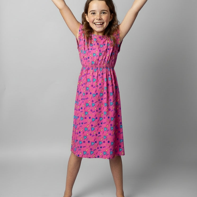 Young girl wearing a pink dress with retro vibe pattern on a white background