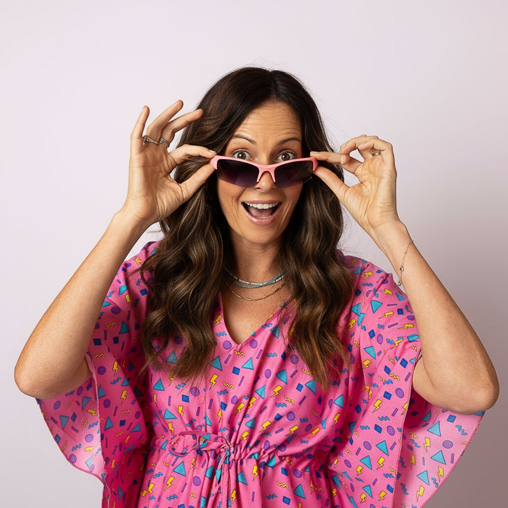 Close-up of woman having fun in the Tropicool Retro Vibe Kaftan, smiling and holding pink sunglasses, showing the bright retro summer print
